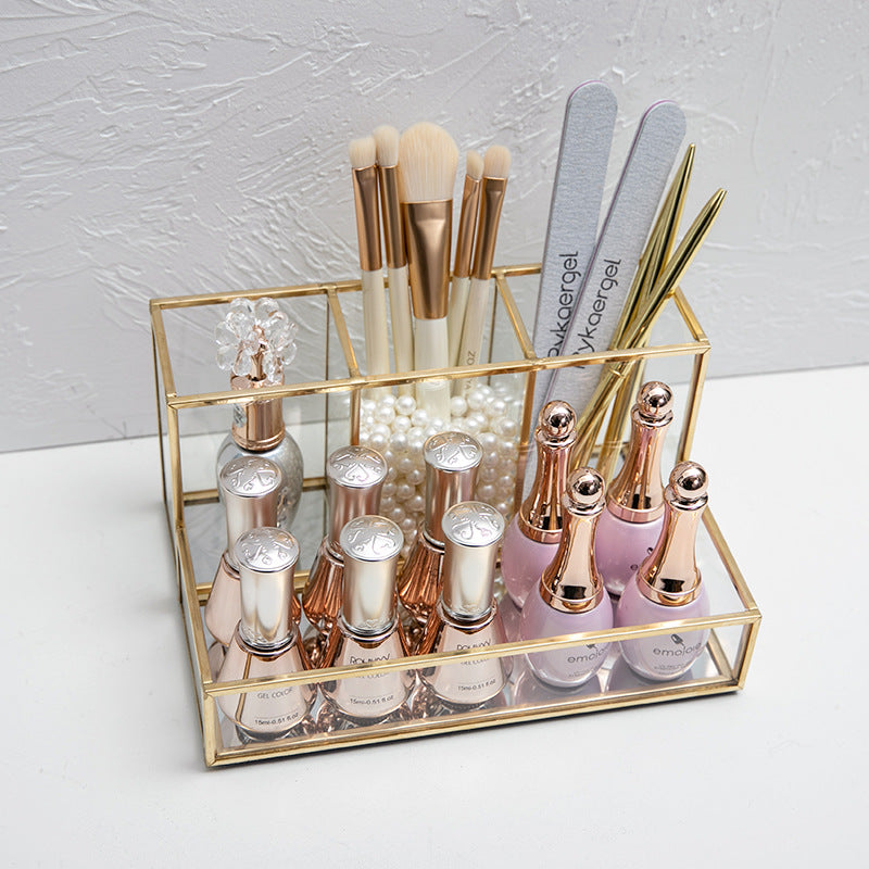Glass makeup organizer with gold metal frame displayed on a bathroom counter, featuring open compartments for cosmetics and b