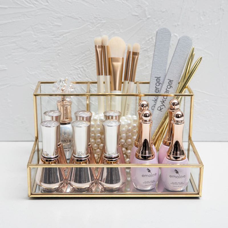 Glass makeup organizer with gold metal frame displayed upright, showing compartments for brushes and beauty products on a bat