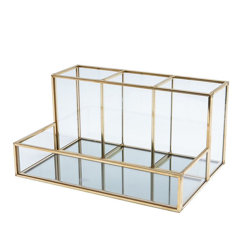 Glass makeup organizer with gold metal frame displayed upright, showing compartments for brushes and beauty products on a bat