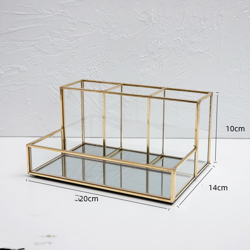 Glass makeup organizer with gold metal frame displayed upright, showing compartments for brushes and beauty products on a bat