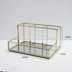 Glass makeup organizer with gold metal frame displayed upright, showing compartments for brushes and beauty products on a bat