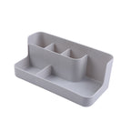 Clear desktop makeup organizer with 5 compartments holding brushes, lipsticks, and skincare products on a vanity surface