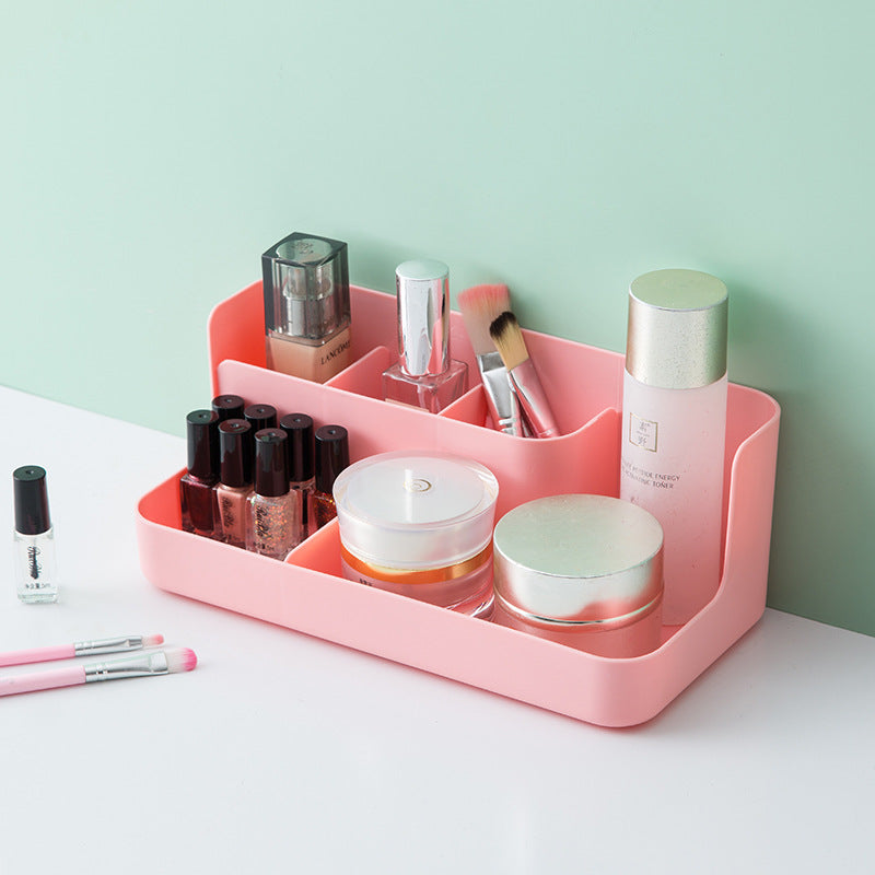 Clear desktop makeup organizer with 5 compartments holding brushes, lipsticks, and skincare products on a vanity