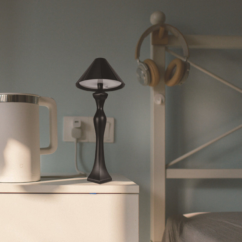 Minimalist LED desk lamp with built-in charging pad on a bedside table, soft warm light illuminating a modern bedroom