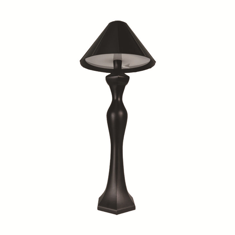 Minimalist LED desk lamp with built-in charging pad shown on a bedside table in a softly lit modern bedroom