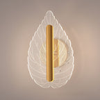 Modern minimalist leaf wall lamp with tri-color LED lighting mounted on an interior wall, shown in warm white glow