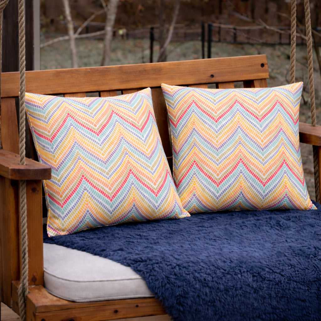 Two waterproof outdoor throw pillows 18x18 displayed on a patio chair, showing fade-resistant fabric and texture detail