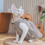 Sphynx cat wearing a soft knit bow dress in a cozy close-up, showing the fitted cat outfit from the front