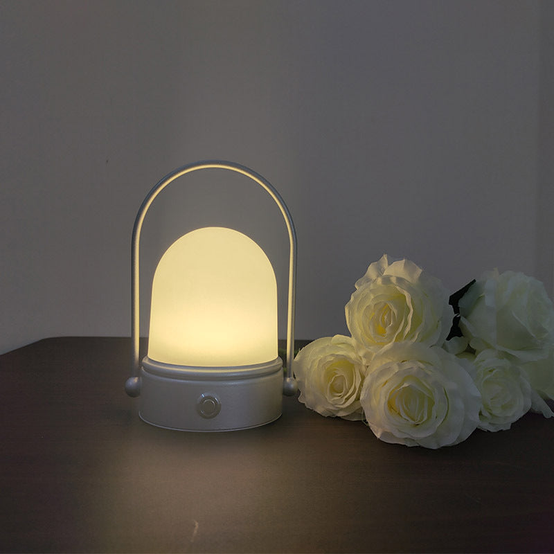 Rechargeable LED atmosphere night light with modern minimalist design, casting a soft warm glow on a bedside table